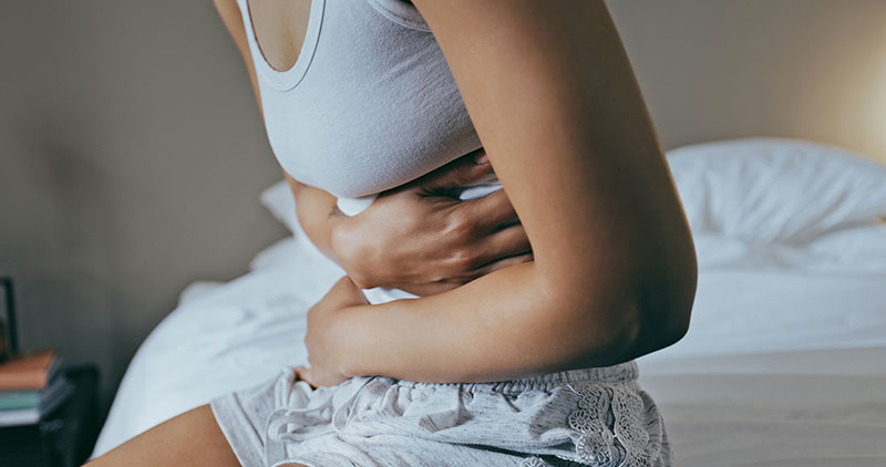 Vrouw die haar buik vasthoudt, wat een probleem met diarree door antibiotica illustreert